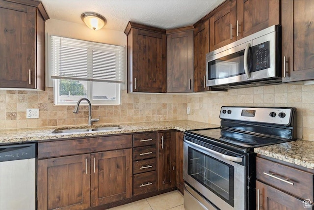330 W 750 N, Clearfield, UT 84015 - kitchen with appliances with stainless steel finishes, light stone countertops, decorative backsplash, light tile patterned floors, and dark brown cabinets