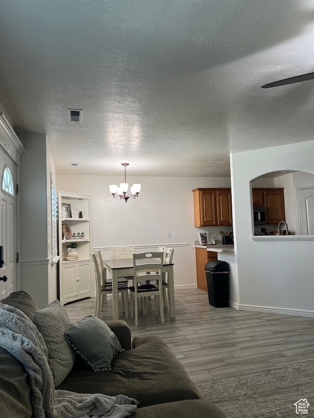 798 W Norway Maple Ct, Payson, UT 84651 - living area with a chandelier, a textured ceiling, arched walkways, and light wood finished floors