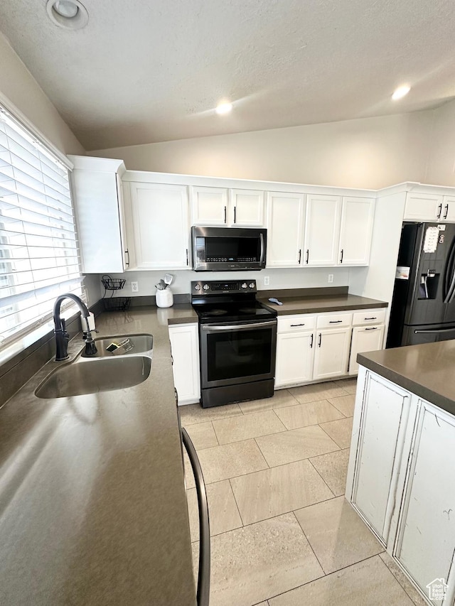 2879 S Fetzer Dr W, Magna, UT 84044 - kitchen with black appliances, vaulted ceiling, white cabinetry, dark countertops, and recessed lighting