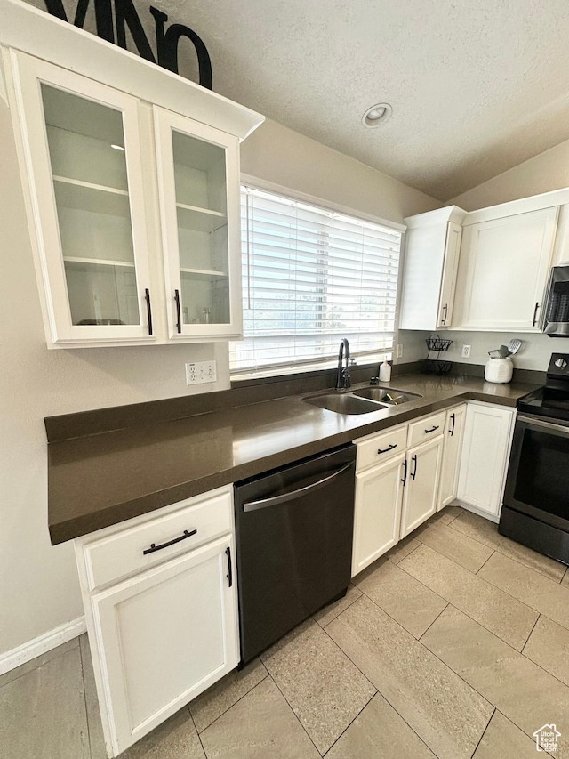 2879 S Fetzer Dr W, Magna, UT 84044 - kitchen with stainless steel appliances, dark countertops, a textured ceiling, white cabinetry, and glass insert cabinets