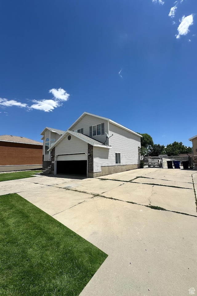 2879 S Fetzer Dr W, Magna, UT 84044 - view of side of home with concrete driveway, an attached garage, and a lawn