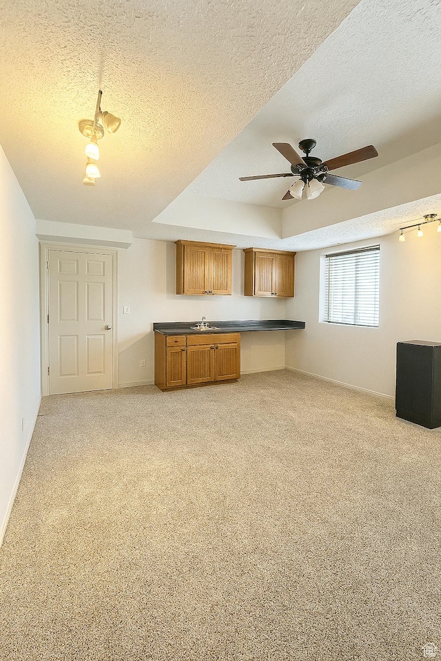 2879 S Fetzer Dr W, Magna, UT 84044 - kitchen with light carpet, a textured ceiling, a ceiling fan, brown cabinetry, and dark countertops