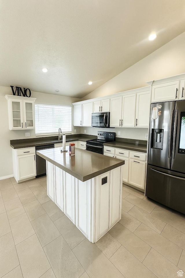 2879 S Fetzer Dr W, Magna, UT 84044 - kitchen with appliances with stainless steel finishes, dark countertops, vaulted ceiling, white cabinets, and light tile patterned flooring