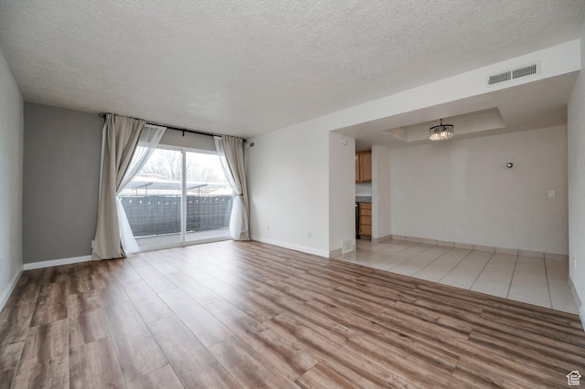 588 E Vine St S Unit 2C, Murray, UT 84107 - unfurnished living room with a textured ceiling, light wood-style flooring, and a chandelier