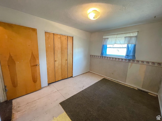 215 N Center St, Castle Dale, UT 84513 - unfurnished bedroom featuring a wainscoted wall, a closet, and a textured ceiling