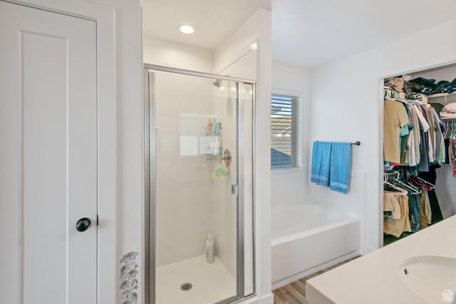 7310 N Green Pasture Ln, Eagle Mountain, UT 84005 - bathroom with a shower stall, a bath, a spacious closet, and wood finished floors