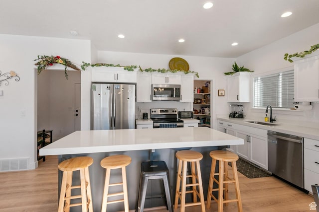 7310 N Green Pasture Ln, Eagle Mountain, UT 84005 - kitchen featuring stainless steel appliances, a breakfast bar, light wood-style flooring, white cabinetry, and recessed lighting