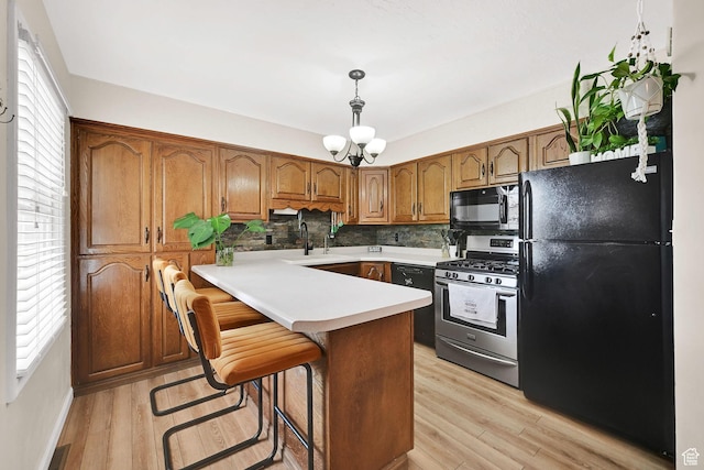 1634 N 350 W, Sunset, UT 84015 - kitchen with black appliances, brown cabinets, light wood finished floors, decorative backsplash, and light countertops