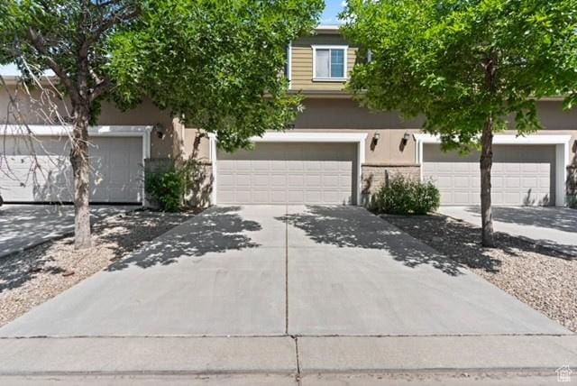 3057 S Finsbury Ln, West Valley City, UT 84120 - view of property hidden behind natural elements featuring driveway, stucco siding, and a garage