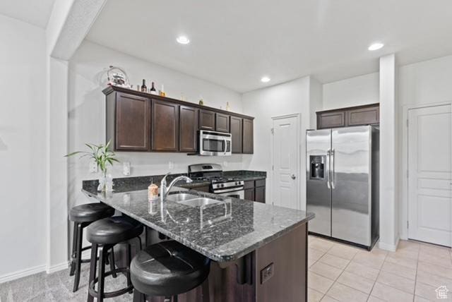 3057 S Finsbury Ln, West Valley City, UT 84120 - kitchen featuring stainless steel appliances, dark brown cabinetry, dark stone counters, a breakfast bar, and recessed lighting
