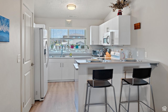 1026 N 1090 W Unit 402, Orem, UT 84057 - kitchen with a peninsula, tasteful backsplash, white appliances, light wood-style flooring, and white cabinetry