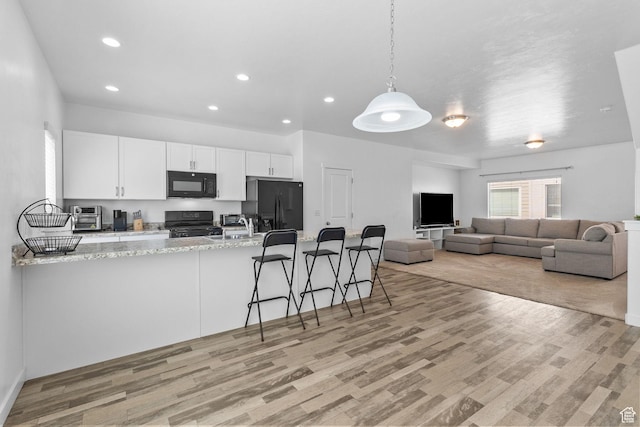 14764 S Rising Star Way W, Bluffdale, UT 84065 - kitchen featuring white cabinets, black appliances, light wood-type flooring, recessed lighting, and a peninsula