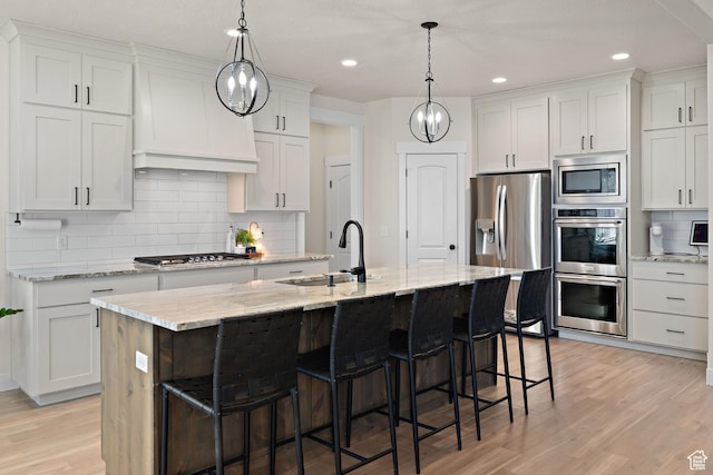 3056 E 80 S, Spanish Fork, UT 84660 - kitchen featuring stainless steel appliances, decorative backsplash, a breakfast bar, light wood-type flooring, and a center island with sink
