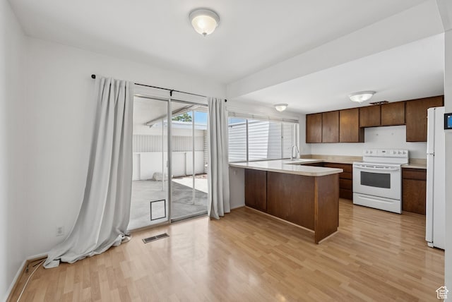 750 E Three Fountains Dr Unit 96, Murray, UT 84107 - kitchen featuring a peninsula, white appliances, light countertops, light wood-style floors, and dark brown cabinetry