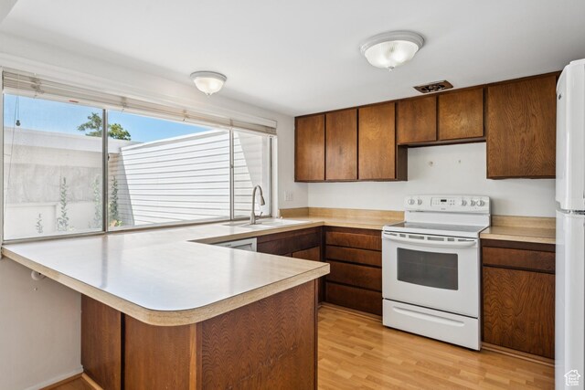 750 E Three Fountains Dr Unit 96, Murray, UT 84107 - kitchen featuring white appliances, a peninsula, light countertops, light wood-style flooring, and brown cabinets