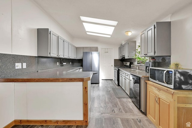 4171 W 2425 N, Hooper Davis Cnty, UT 84315 - kitchen with vaulted ceiling, stainless steel appliances, light wood-type flooring, decorative backsplash, and a peninsula