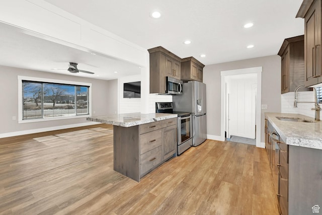 648 W Porter Ln, Centerville, UT 84014 - kitchen featuring stainless steel appliances, tasteful backsplash, light wood-style flooring, recessed lighting, and light stone counters