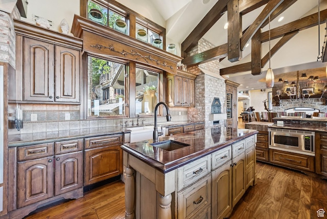 10399 Summit View Dr N, Park City, UT 84060 - kitchen featuring a kitchen island with sink, decorative backsplash, dark wood-style flooring, beam ceiling, and stainless steel microwave