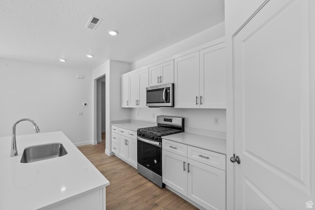 1391 S Padre Bay Dr Unit 4075, Washington, UT 84780 - kitchen with appliances with stainless steel finishes, white cabinetry, light wood finished floors, light countertops, and recessed lighting