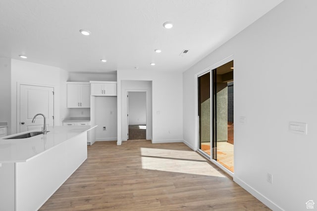 1391 S Padre Bay Dr Unit 4075, Washington, UT 84780 - kitchen with white cabinets, light countertops, recessed lighting, light wood-style floors, and a kitchen island with sink