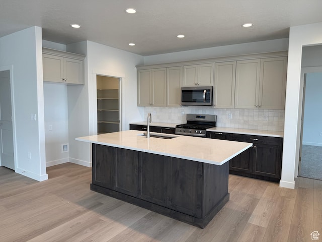 22 S 3830 W Unit 422, West Point, UT 84015 - kitchen featuring appliances with stainless steel finishes, light wood-type flooring, decorative backsplash, a kitchen island with sink, and recessed lighting