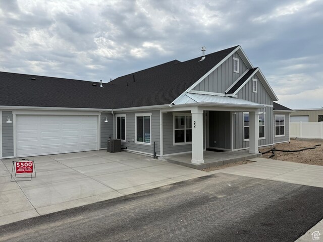 22 S 3830 W Unit 422, West Point, UT 84015 - view of front of property featuring board and batten siding, roof with shingles, driveway, a garage, and a porch