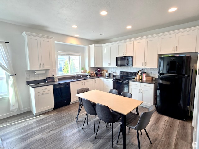 5381 W Mount Maclure Pl, Herriman, UT 84096 - kitchen with black appliances, dark countertops, white cabinets, tasteful backsplash, and light wood-type flooring