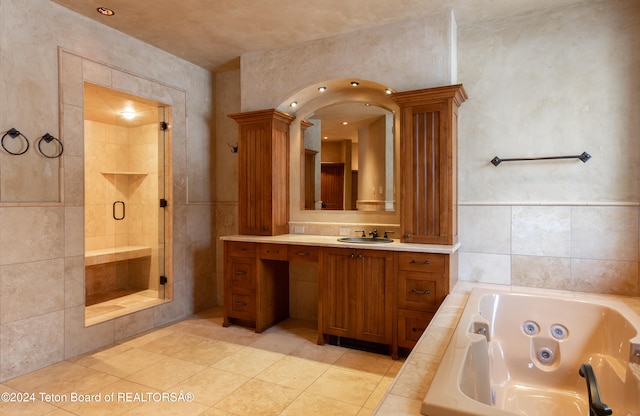 bathroom with shower with separate bathtub, vanity, tile patterned floors, and tile walls