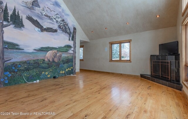 living room featuring a fireplace, light hardwood / wood-style flooring, and high vaulted ceiling