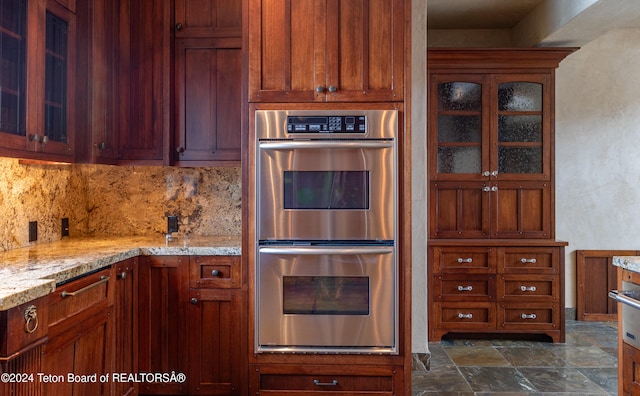 kitchen featuring backsplash, light stone counters, and double oven