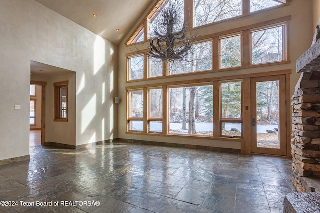 unfurnished living room with high vaulted ceiling and a notable chandelier