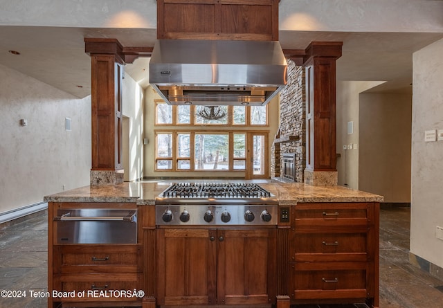 kitchen with light stone countertops, ornate columns, stainless steel gas cooktop, and exhaust hood