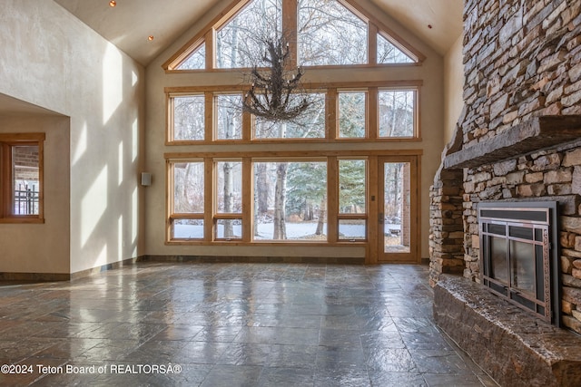 unfurnished living room with a fireplace, high vaulted ceiling, and plenty of natural light