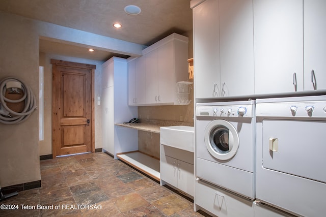 laundry room with washing machine and clothes dryer and cabinets