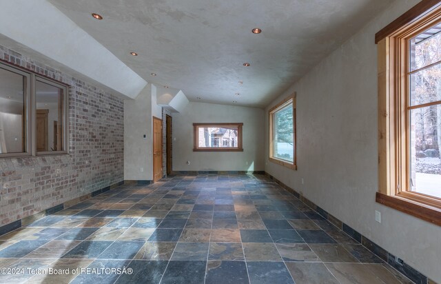 unfurnished living room featuring a wealth of natural light and vaulted ceiling