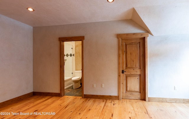 unfurnished bedroom with hardwood / wood-style floors and ensuite bath