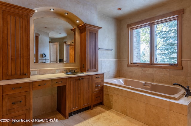 bathroom featuring tile patterned flooring, vanity, and tiled tub