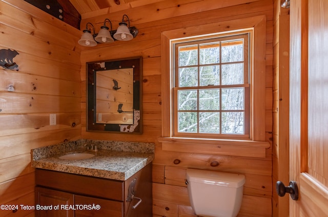 bathroom featuring vanity, vaulted ceiling, toilet, and wooden walls