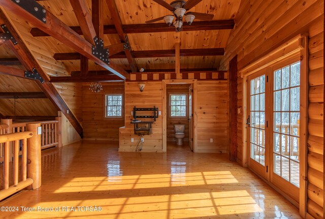 interior space with plenty of natural light, light wood-type flooring, and wooden walls