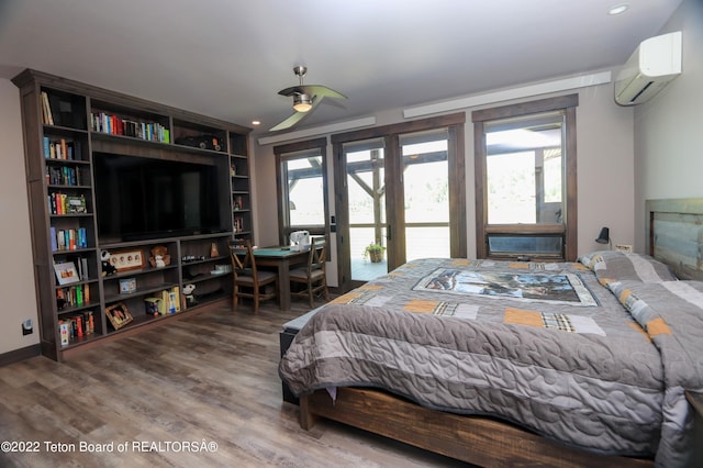 bedroom featuring a wall unit AC, access to outside, hardwood / wood-style flooring, and ceiling fan