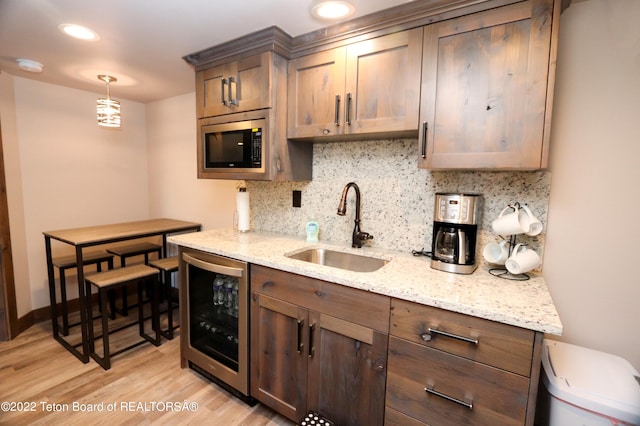 kitchen featuring sink, beverage cooler, stainless steel microwave, and light hardwood / wood-style floors