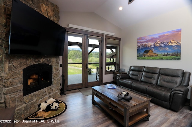 living room with a stone fireplace, hardwood / wood-style flooring, lofted ceiling, and french doors