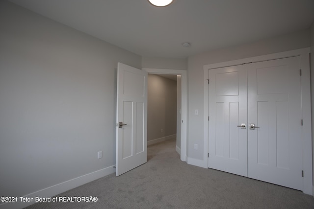 unfurnished bedroom featuring light carpet and a closet