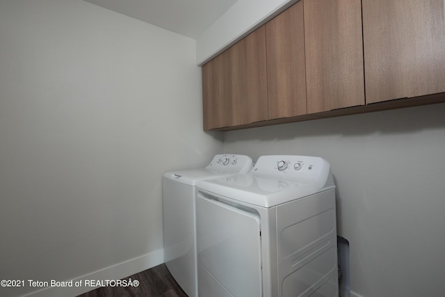 laundry room featuring washer and dryer, dark hardwood / wood-style flooring, and cabinets