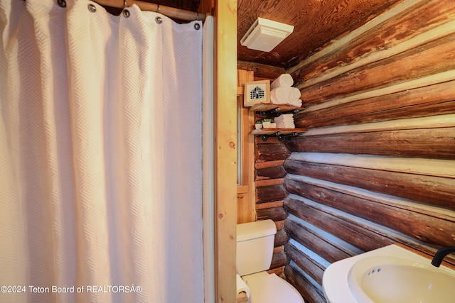 bathroom with rustic walls, sink, and toilet