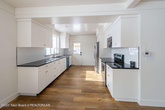 kitchen featuring backsplash, light hardwood / wood-style floors, sink, stainless steel appliances, and white cabinets