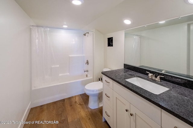 full bathroom with hardwood / wood-style floors, shower / tub combo with curtain, vanity with extensive cabinet space, and toilet