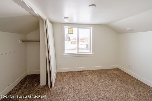 additional living space with dark carpet and vaulted ceiling