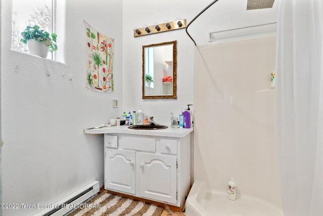 bathroom with baseboard heating, vanity, hardwood / wood-style flooring, and a shower