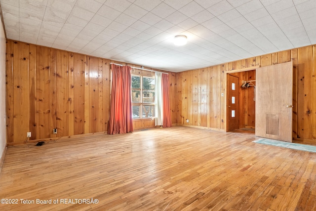 spare room featuring wood walls and light hardwood / wood-style flooring